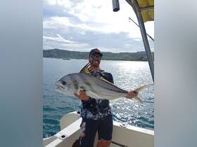 A proud angler displays his impressive catch aboard a boat, showcasing the thrill of fishing in beautiful waters.