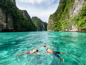 A group of snorkelers enjoys the crystal-clear waters surrounded by stunning cliffs, perfect for exploring marine life in a tropical paradise.