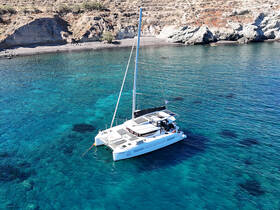 A stunning aerial view of a catamaran named 'Sophia' anchored in crystal-clear waters, surrounded by a picturesque coastline — perfect for serene sailing adventures.
