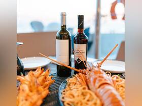 A beautifully arranged seafood platter featuring lobster and pasta, complemented by Santorini wines — perfect for an upscale dining experience on a boat.