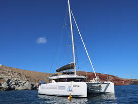 A stunning view of the catamaran 'Sophia' docked in serene waters, showcasing its sleek design against a backdrop of rocky terrain.