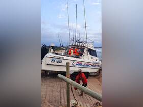 Crew members prepare the Pelagic Hunter charter boat for a fishing trip, showcasing the excitement of boat launches and fishing adventures.
