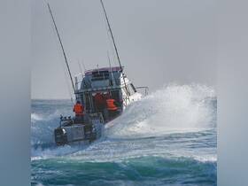 A fishing boat navigates through the waves with crew members in action, showcasing the thrill of ocean adventures.