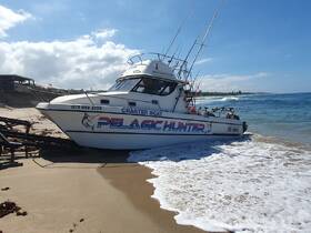 The Pelagic Hunter charter boat is seen docked on the beach, ready for fishing adventures along the coast.