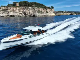 A sleek speedboat named Saxdor glides through the clear blue waters, showcasing its elegant design and powerful performance against a stunning coastal backdrop.