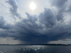 A dramatic sky over the water, featuring clouds and sunlight, creating an atmospheric scene. Ideal for capturing the beauty of nature.