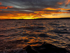 A stunning sunset over the water, showcasing vibrant hues reflecting on the waves — perfect for serene evening boat rides.