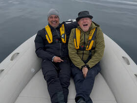 Two friends share a joyful moment on a boat, showcasing the fun and camaraderie of a day on the water.