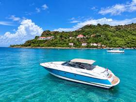A stunning view of a yacht anchored in crystal-clear turquoise waters, surrounded by lush greenery and picturesque hills, perfect for showcasing luxury boating experiences.