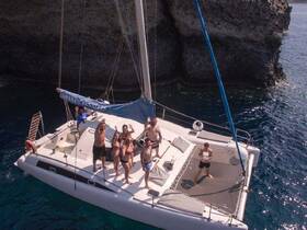 A lively group celebrates aboard a catamaran, waving and enjoying the sun — perfect for memorable outings and adventures on the water.