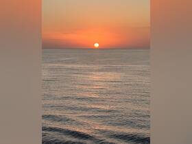 A stunning sunset over calm waters, creating a serene backdrop perfect for evening boat cruises.
