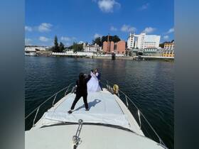 A beautiful couple poses for wedding photos on the deck of a boat, capturing a memorable moment against a picturesque waterfront backdrop.