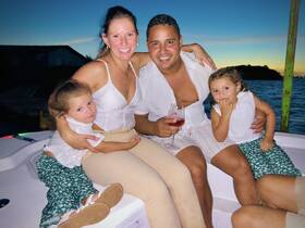 A joyful family enjoys a sunset boat ride, celebrating together with drinks and laughter — a perfect moment for creating lasting memories on the water.