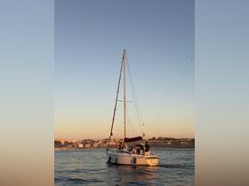 A group enjoys a sailing experience at sunset aboard a yacht, with a picturesque coastal backdrop enhancing the ambiance.