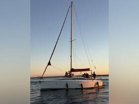A group waves from the deck of the 'Lua da Afurada' sailboat during a picturesque sunset, capturing the essence of a joyful sailing experience.