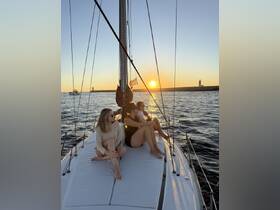 A group of friends enjoys a stunning sunset while relaxing on the deck of a sailboat, creating the perfect atmosphere for memorable sailing experiences.
