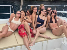 A joyful group of friends relaxes on a boat, enjoying their time together in swimsuits — perfect for a fun day on the water.