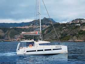 A sleek Bali catamaran navigates the serene waters, showcasing its elegant design against a picturesque coastal backdrop.