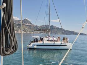 A lively group enjoys time aboard a catamaran, showcasing the perfect setting for celebrations and on-water activities against a stunning coastal backdrop.