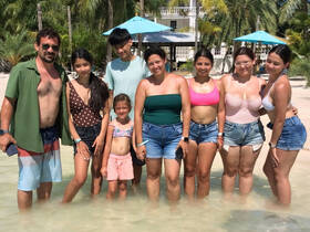 A joyful group of family and friends enjoys a sunny day at the beach, wading in the shallow water — perfect for memorable summer outings.