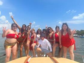 A vibrant group of friends celebrates aboard a boat, all dressed in stylish red swimwear, capturing the joy of a fun day on the water.