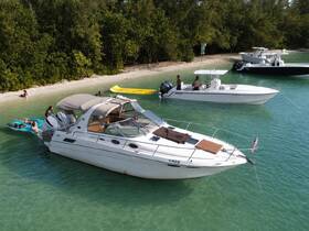 A lively scene at a beach with groups enjoying the water and relaxing on a boat, perfect for summer fun and water activities.