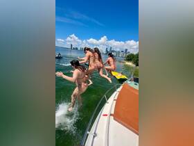 A group of friends joyfully jumps into the water from a boat, capturing the essence of summer fun and adventure on the water.
