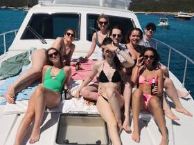 A lively group of friends enjoys a sunny day on a yacht, lounging and celebrating with drinks — the perfect backdrop for summer fun on the water.