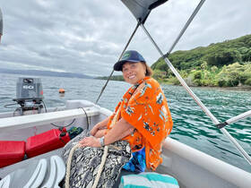 A cheerful woman enjoys a scenic boat ride, surrounded by lush greenery and calm waters — perfect for exploring coastal beauty.