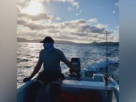 A fisherman navigates a boat under a stunning sunset, showcasing the thrill of ocean adventures and fishing experiences.