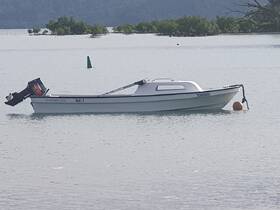 A small boat is docked in calm waters, showcasing its sleek design and motor, perfect for leisurely outings or fishing trips.