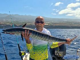 A proud angler holds up a large fish caught during a fishing charter in the ocean, showcasing the thrill of deep-sea fishing adventures.