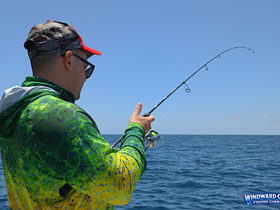 A fisherman casts his line into the open ocean, showcasing the thrill of fishing adventures on the water.