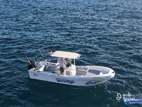 A fishing charter boat, 'Windward Catch,' is seen cruising through the clear waters, perfect for an adventurous day on the sea.