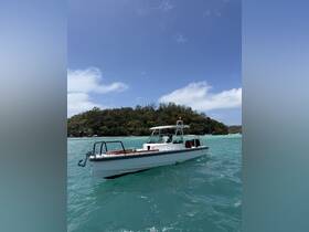 A sleek boat navigates through clear turquoise waters, showcasing its elegant design against a lush island backdrop.
