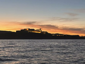 A stunning sunset view of a historic landmark silhouetted against the vibrant sky, perfect for capturing the beauty of evening boat trips.