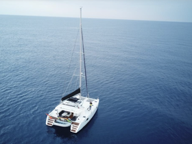 Aerial view of a sleek catamaran sailing through calm blue waters, showcasing its elegant design and perfect for leisurely cruises.