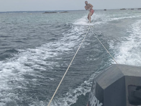 A man enjoys wakeboarding behind a boat, showcasing thrilling water sports action in the ocean.