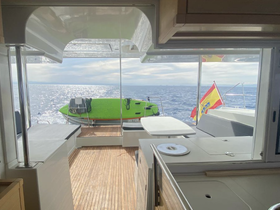 A view from inside the cabin of a boat, showcasing the helm area and a green dinghy outside, perfect for exploring coastal waters.