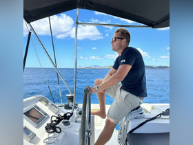 A man sits at the helm of a boat, enjoying the view of the open water and distant islands — perfect for navigating the seas in style.