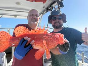 Two anglers proudly display their impressive catch aboard a fishing boat, showcasing the thrill of a successful day on the water.