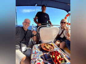 A cheerful group enjoys drinks and snacks aboard a sailboat, capturing the essence of a perfect sailing adventure with friends.
