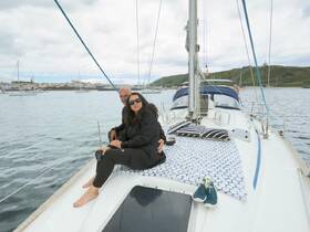 A couple enjoys a relaxing moment on the deck of a yacht, surrounded by scenic waterfront views — perfect for romantic getaways or leisurely sailing adventures.