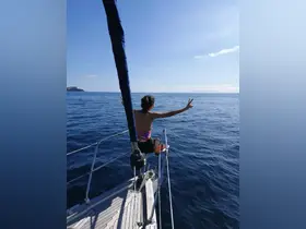 A joyful moment captured as a woman enjoys the ocean breeze while sailing, showcasing the thrill of adventure on the water.