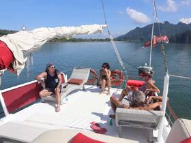 A group of friends relaxes on the deck of a sailboat, enjoying the serene waters and beautiful scenery — perfect for a day of leisure on the water.