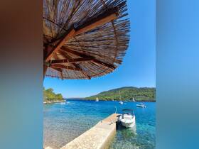 A serene view of a small boat docked at a picturesque waterfront, surrounded by lush greenery and clear blue waters — perfect for a relaxing day by the sea.
