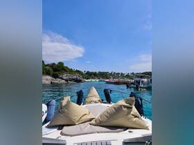 A serene view from the front of a yacht, showcasing comfortable seating and a picturesque backdrop of a tropical shoreline, perfect for relaxation and enjoying the sun.