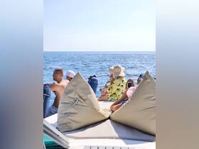 A group of friends enjoys a relaxing day on the water, capturing moments on their phones while lounging on a boat. Perfect for summer outings and memorable adventures.