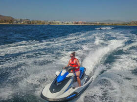 A thrilling moment captured as a woman rides a jet ski through the waves, showcasing the excitement of water sports and adventure on the open sea.