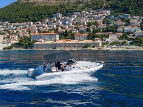 A speedboat glides through clear waters, showcasing the stunning coastline and vibrant hillside homes — perfect for exploring scenic destinations.